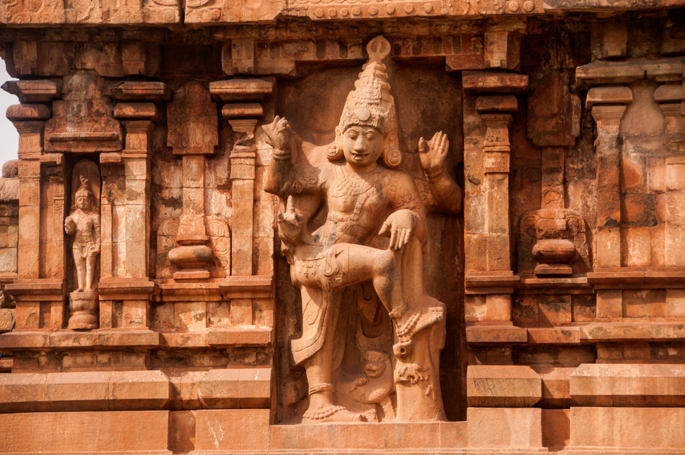 A monumental dvarapala — a temple guardian — carved into a niche on the lower vimana wall